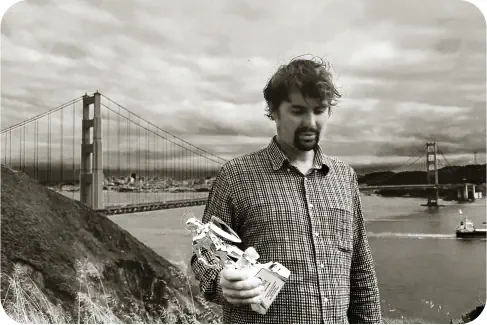 Image of Ivan in front of bridge holding an award