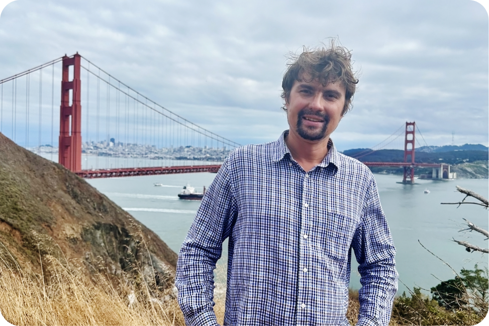 Image of Ivan in front of bridge holding an award